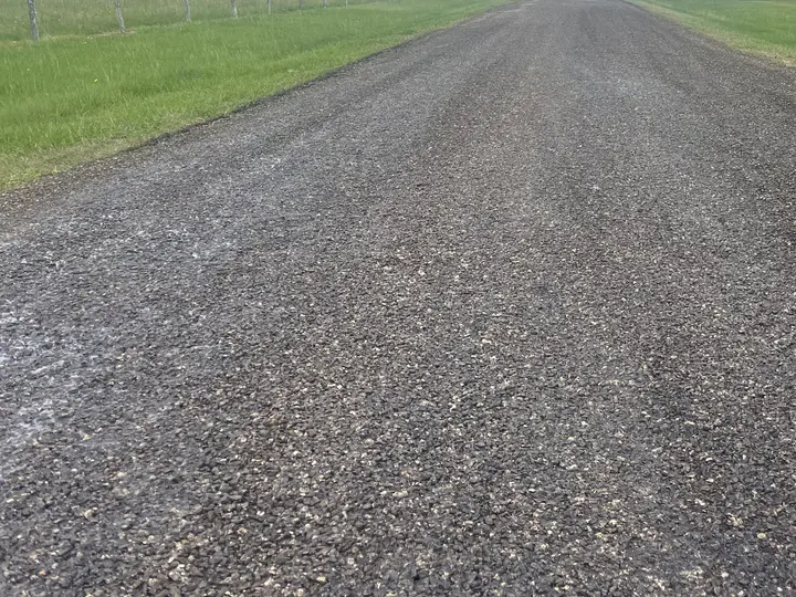 Chip seal ranch road running along a pasture fence line